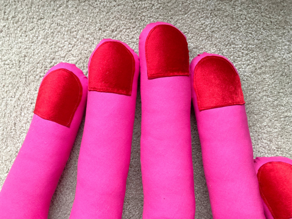 Close-up of the red fingertips on a pink mini hand pillow