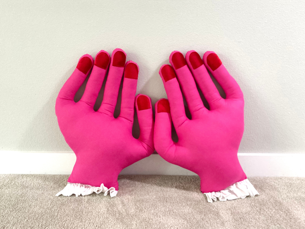 Two pink mini hand pillows with red fingertips side by side
